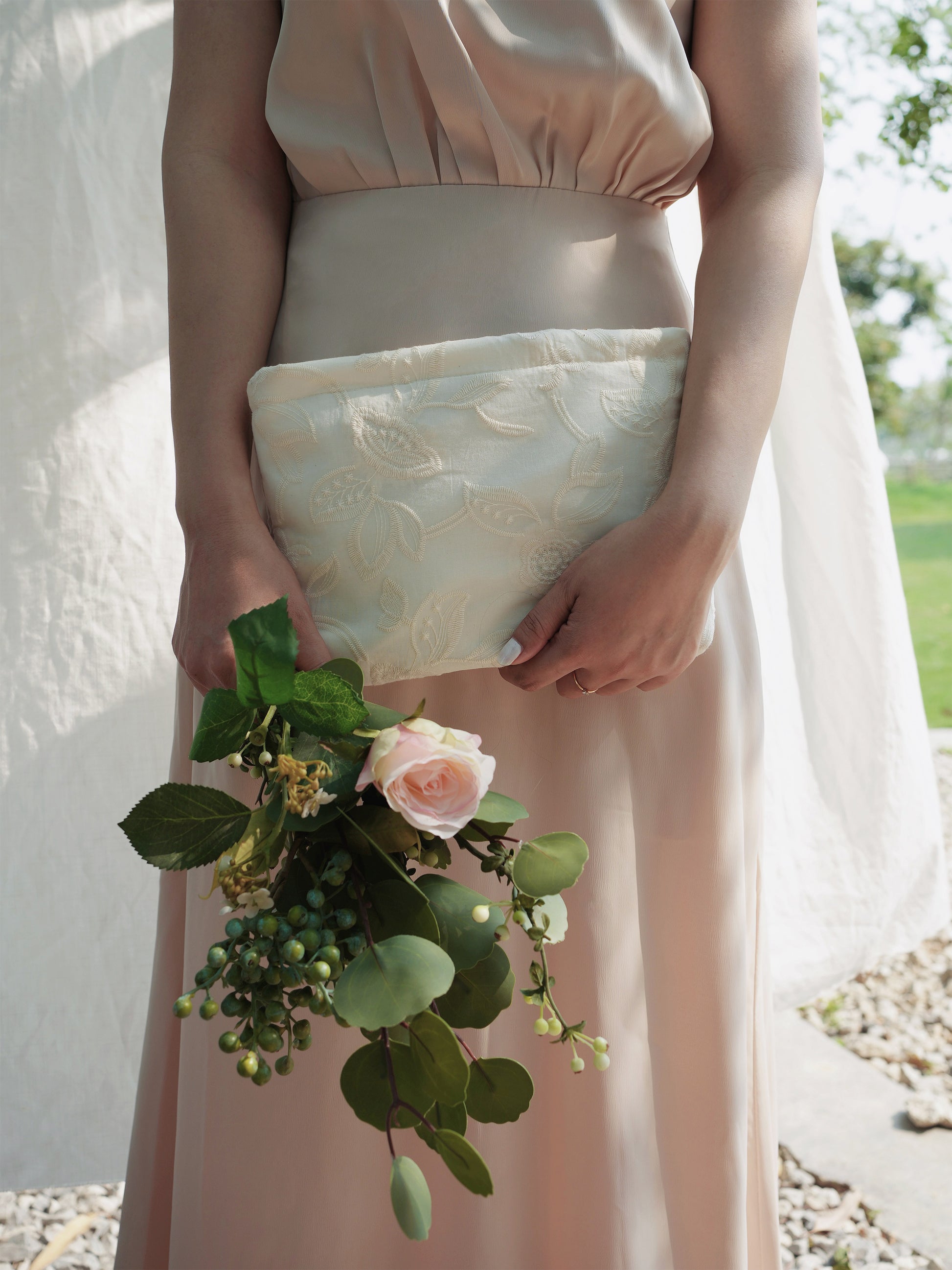 Bridesmaids holding clutch bag and bouquet of flowers outdoors